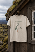 Exact Sand Gildan 3000B youth Atlantic Puffin Field Notes tee hanging outside an Icelandic turf-roof cabin; full front view
