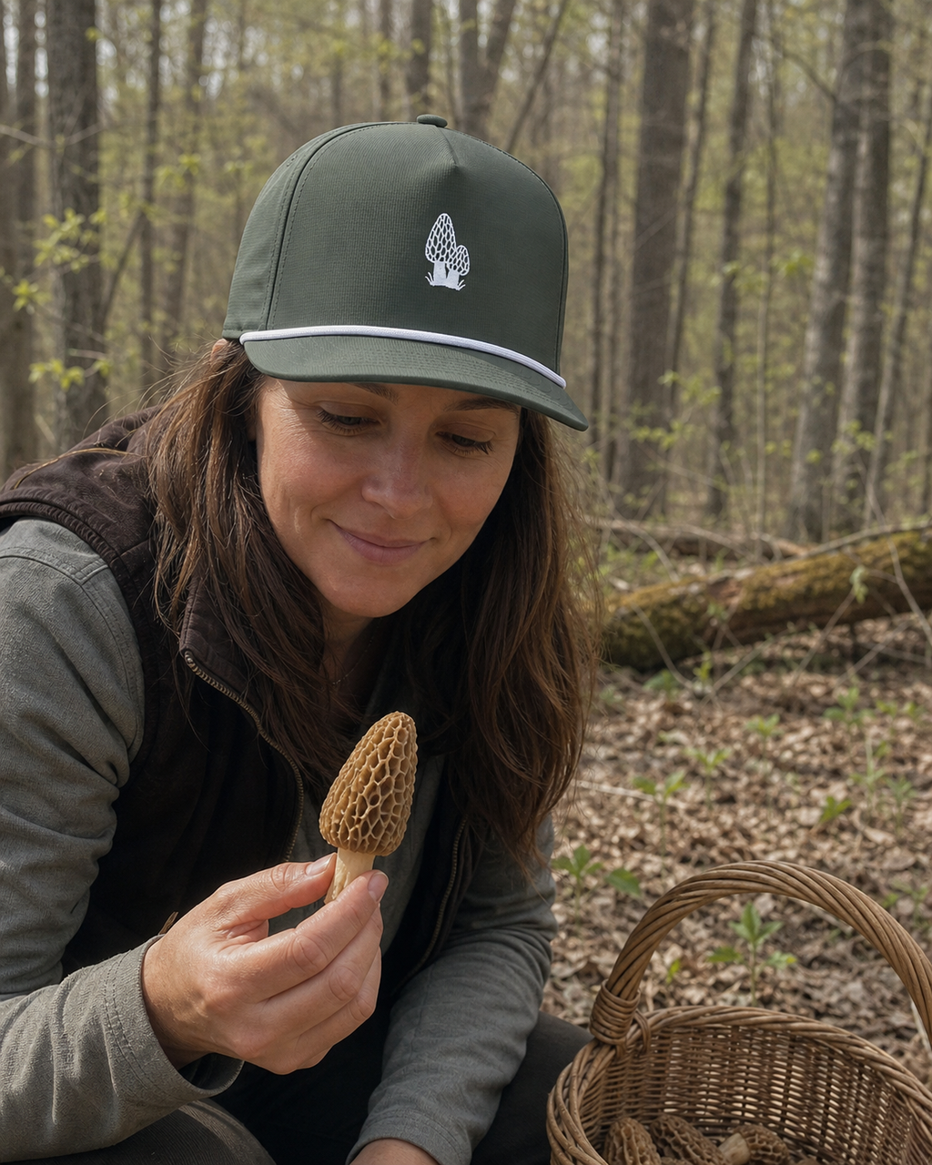 Person wearing the Moss Morel Forager Sunwashed Rope Cap with white morel embroidery while foraging in a northwoods forest
