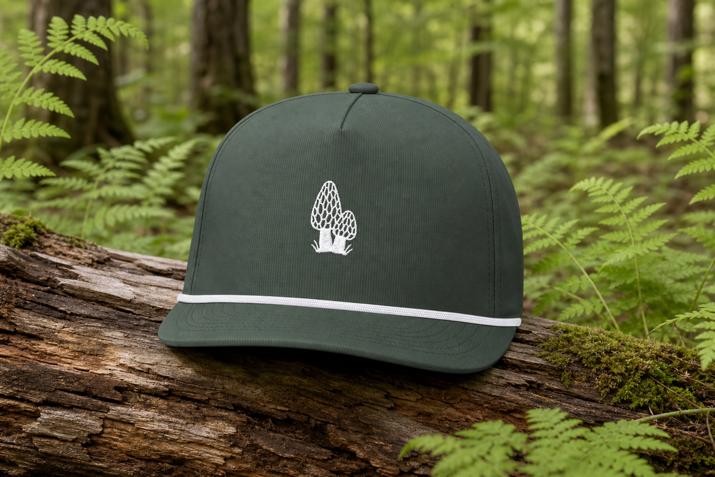 Moss Morel Forager Sunwashed Rope Cap with white morel embroidery and white rope on a northwoods cedar log